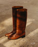 A pair of tall, brown leather boots with a smooth texture, rounded toes, and low black heels.  5