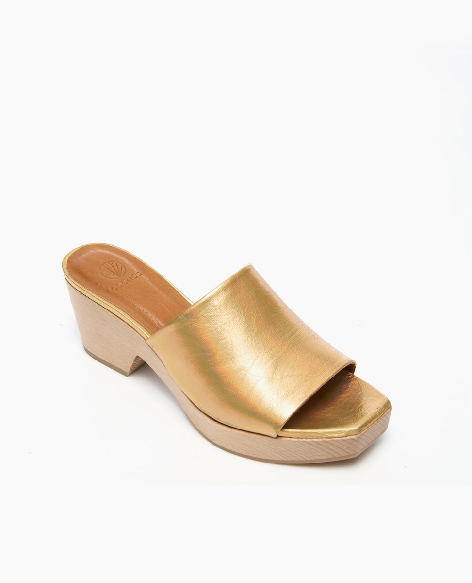 A gold, open-toe mule sandal with a wide, smooth leather strap and a wooden block heel.