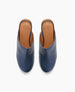 A pair of sleek, navy blue leather mules with a smooth texture, featuring a rounded toe and tan leather insoles embossed with a logo. 4