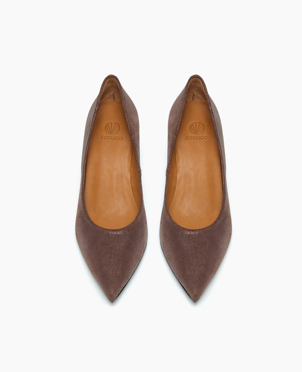 A pair of brown, pointed-toe leather flats with a smooth texture, featuring a tan insole and a subtle logo imprint on the heel area.