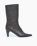 A sleek, black, mid-calf leather boot with a pointed toe, smooth texture, and a tapered, angular heel. 2