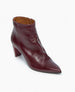 A sleek, dark burgundy ankle boot with a pointed toe, textured glossy leather finish, and an angled heel, featuring a tan interior lining. 7