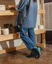 A person wearing a denim outfit and green boots is arranging ceramic bowls on a wooden shelf. 4