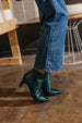 A person wearing blue jeans and black pointed-toe ankle boots stands on a polished concrete floor. 5