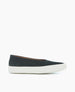 A sleek, black slip-on shoe with a smooth, matte finish, featuring a rounded toe, a low-cut design, and a contrasting white rubber sole. 2