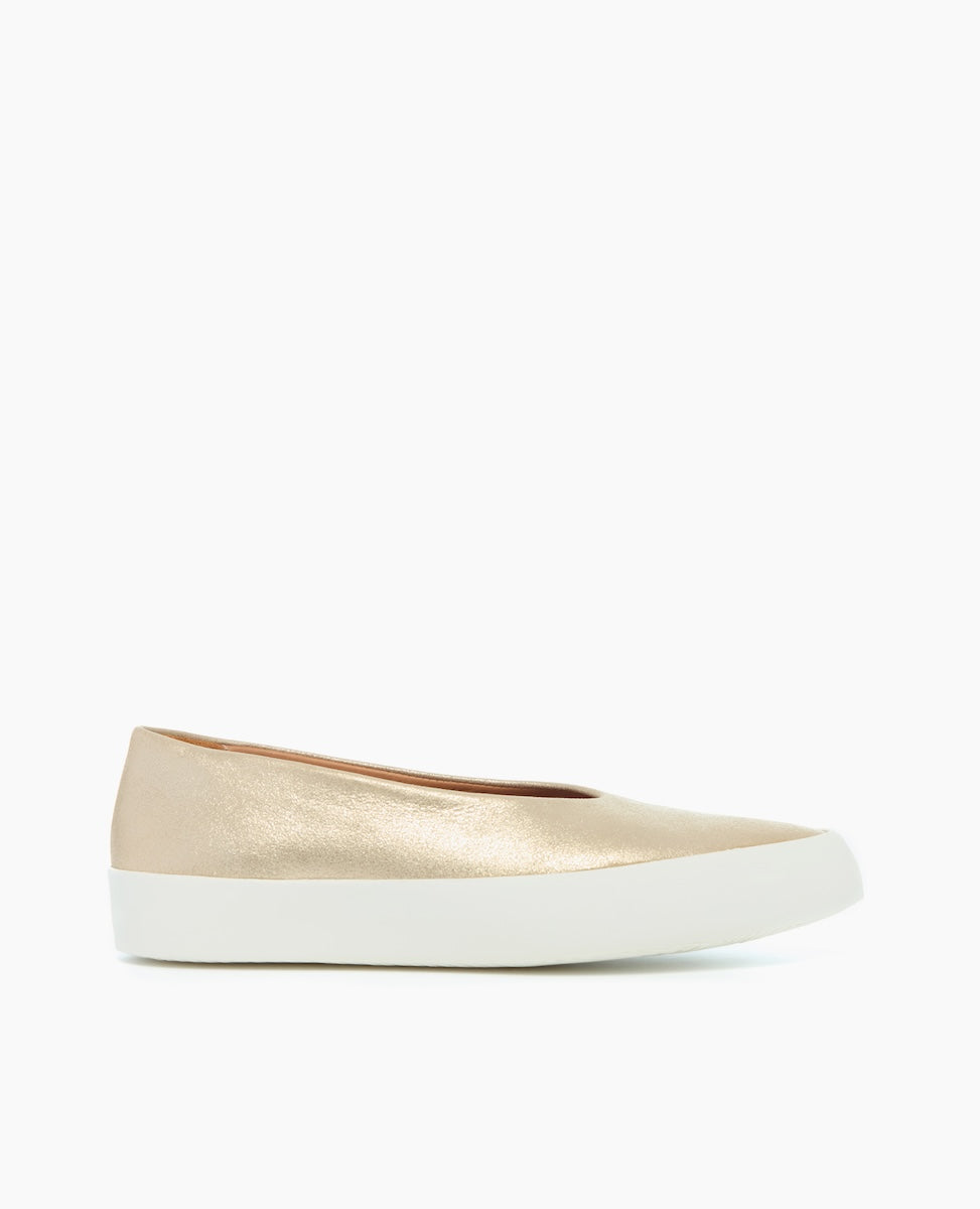 A sleek, gold-colored flat shoe with a smooth, metallic finish, featuring a rounded toe, a low-cut vamp, and a thick white rubber sole.