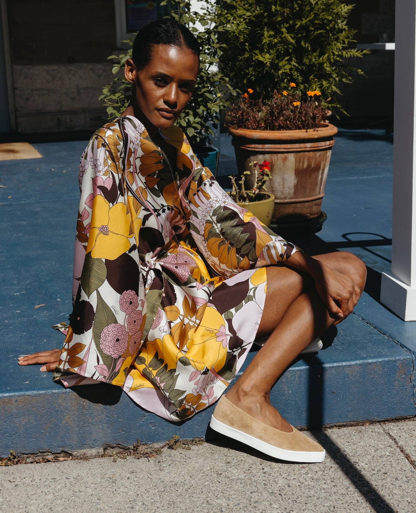 Woman sitting down outside with her right leg bent and wearing the Regal in Tobacco.