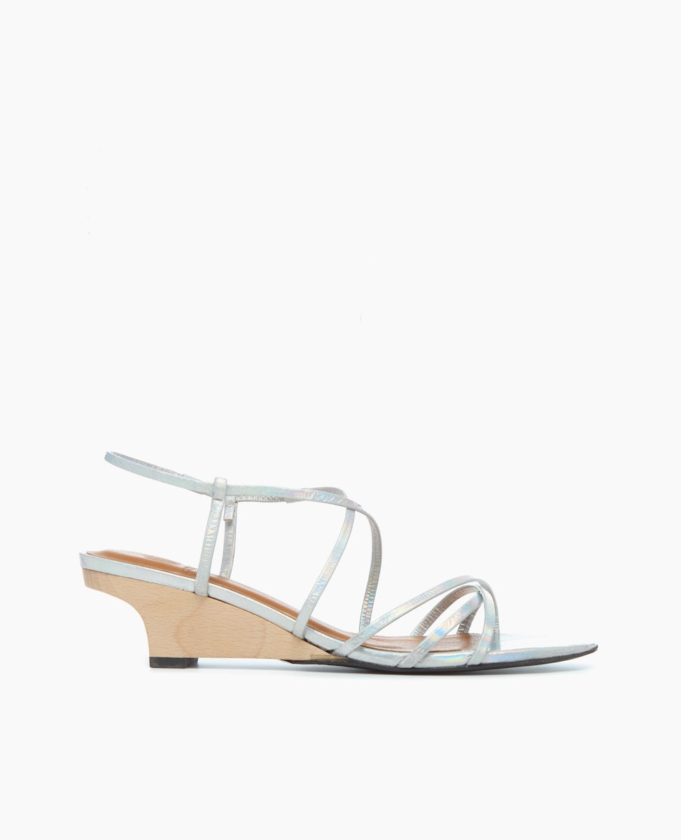 A sleek, silver strappy sandal with a low, light wooden wedge heel, featuring thin metallic straps and a minimalist design.