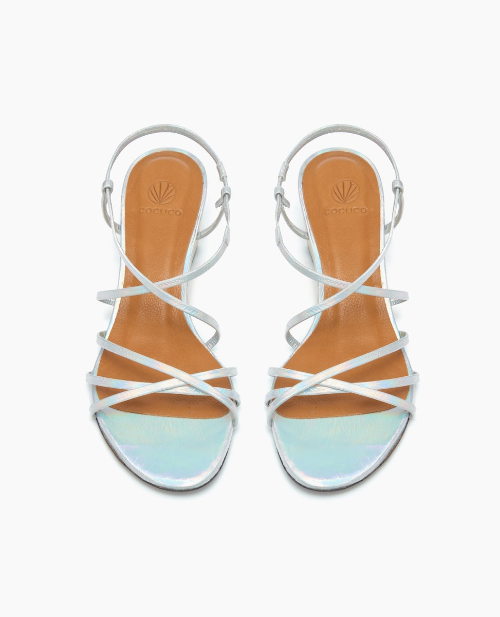 Strappy sandals with iridescent toe straps, tan insoles, and thin white ankle straps, featuring a sleek and minimalist design.