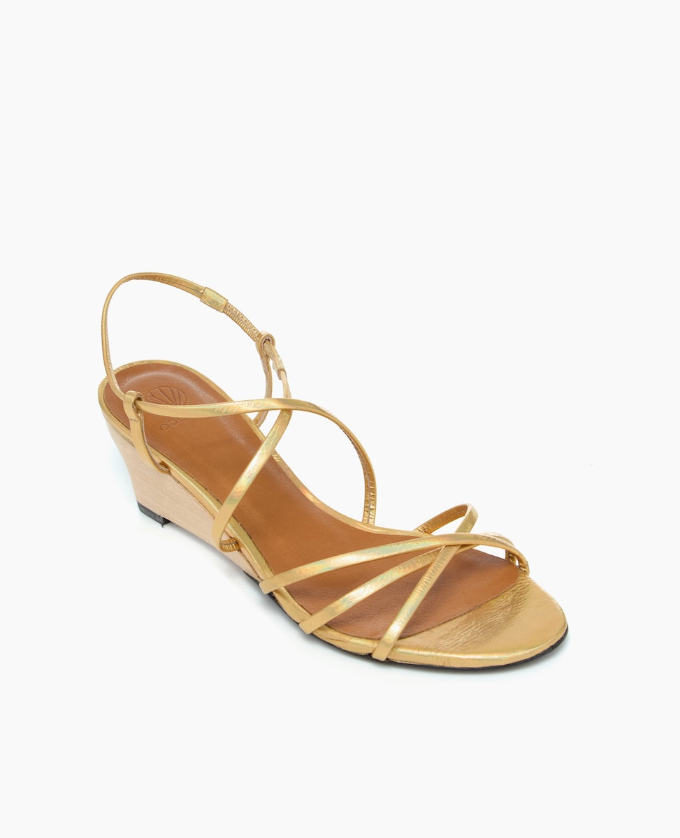 A tan wedge sandal featuring thin, crisscrossing leather straps, an adjustable ankle strap, a smooth wooden wedge heel, and a lightly textured sole.