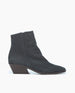 A sleek, black suede ankle boot with a pointed toe, a low, angled block heel, and a smooth, matte finish. 4