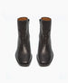 A pair of sleek, black leather ankle boots with side zippers, displayed against a plain white background. 3