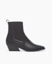 A sleek, black ankle boot with a squared toe, low angled block heel, smooth leather finish, elastic side panels, and a pull tab at the back. 1