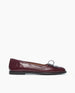 A single burgundy leather flat shoe with an architectural loop detail on the toe, displayed against a plain white background. 4