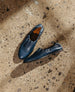 A pair of dark blue, slip-on shoes with elasticized openings are placed on a speckled concrete floor, casting soft shadows. 6