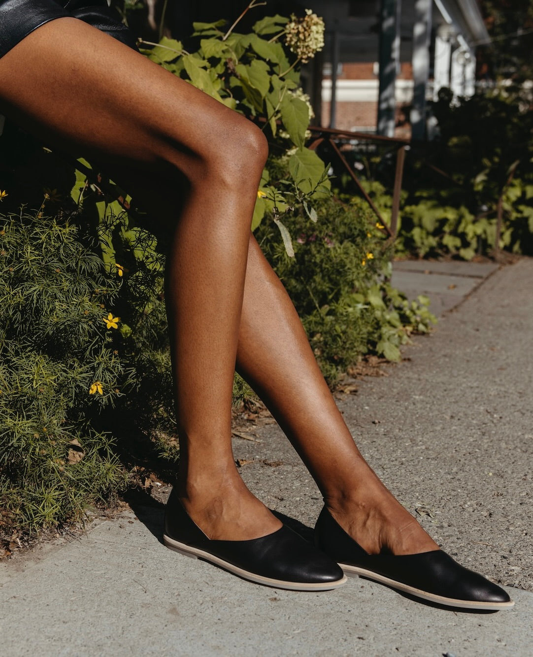 Bent legs and feet against foliage waring the Yen Flat in Black. 