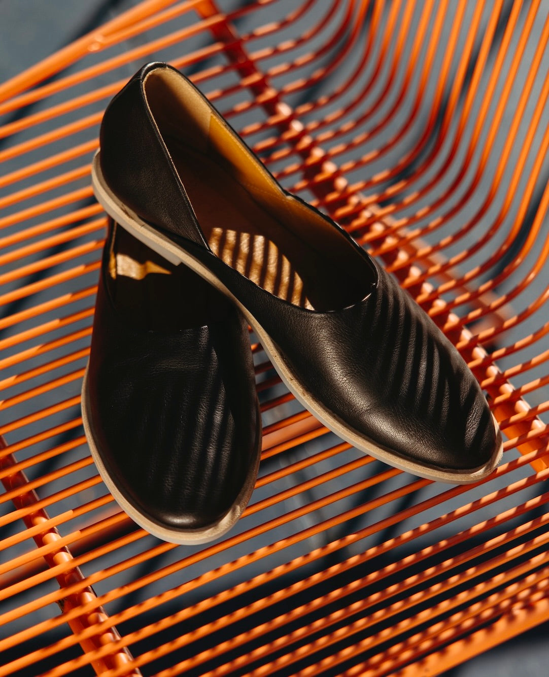 The Yen Flat in Black against an orange chair. 