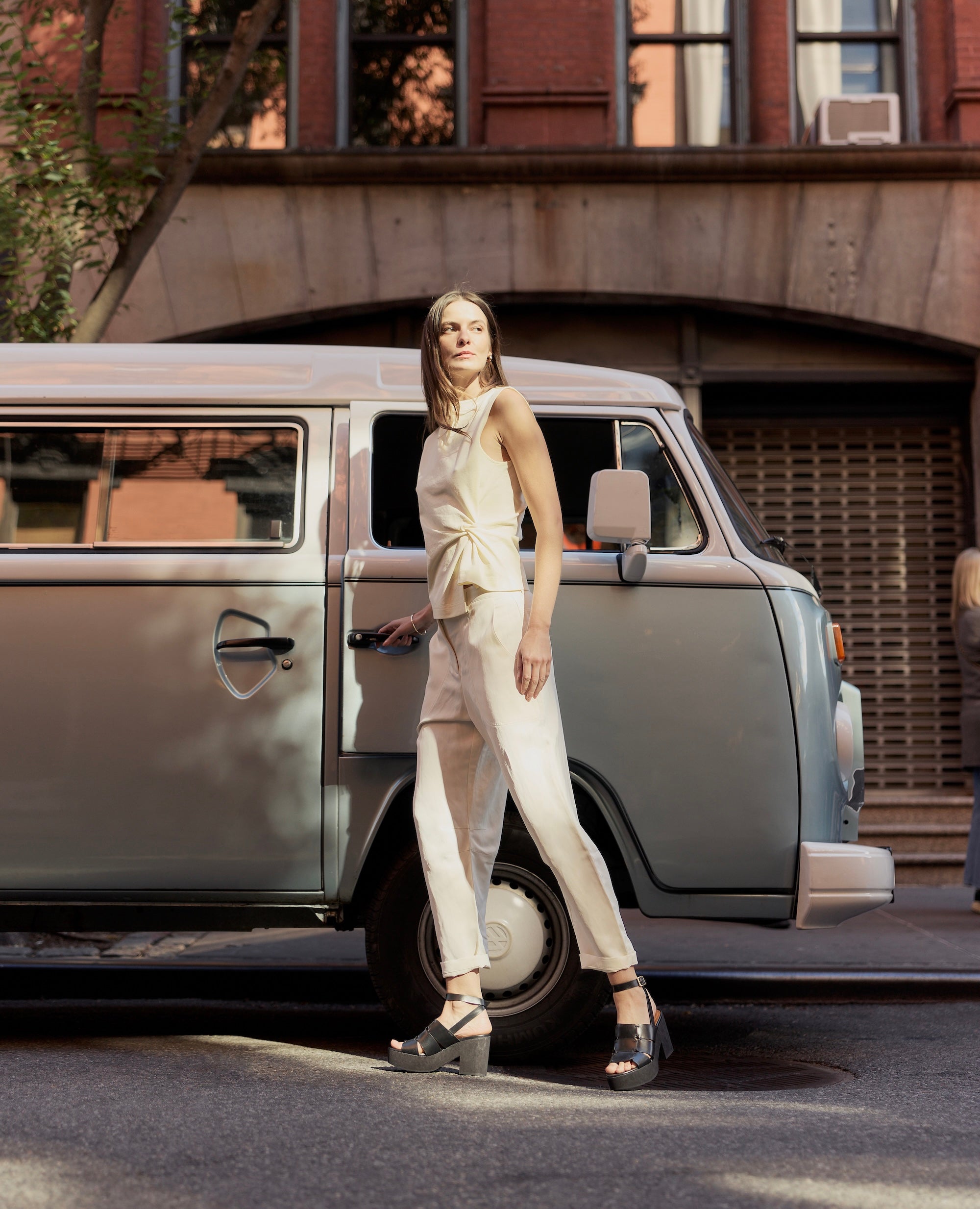 Woman standing next to a vintage van in an urban setting