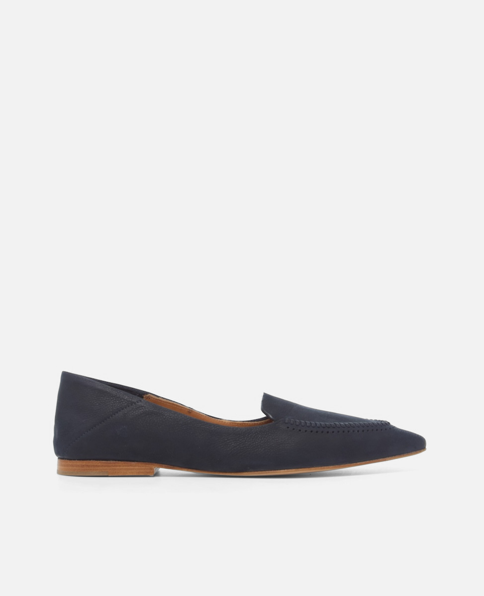 Side view of a pointed-toe navy nubuck leather loafer with topstitch detailing and a flat leather sole on a white background