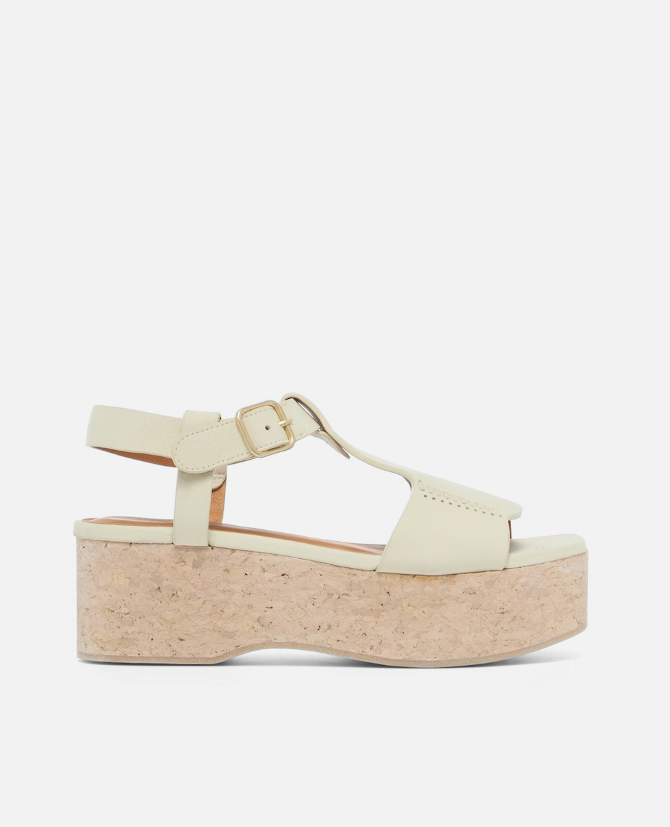 Side view of a white nubuck leather wedge sandal with wide stitched straps, adjustable ankle buckle, and a whitewashed cork platform sole