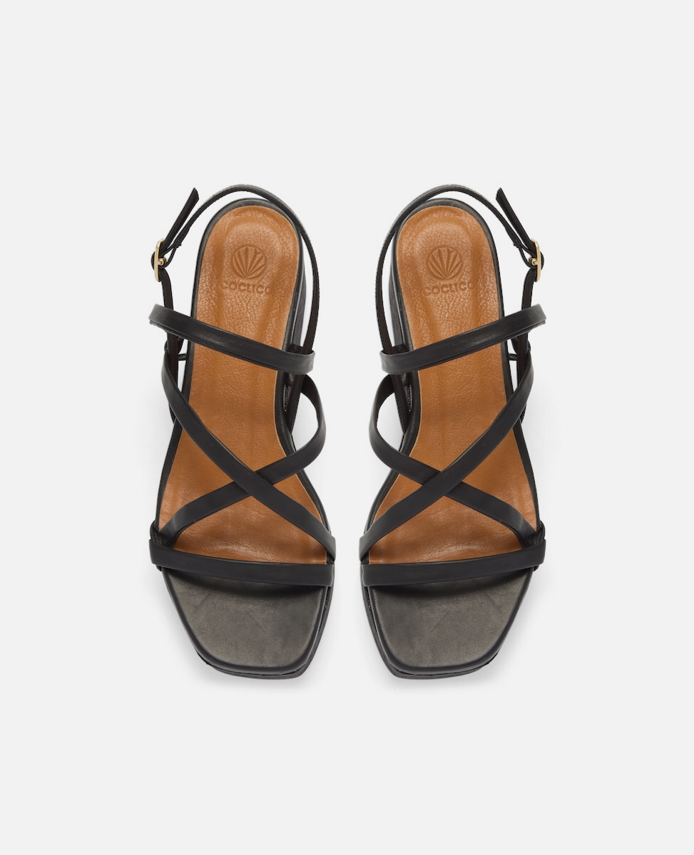 Top view of a black leather cork wedge sandal with slim crisscross straps, adjustable slingback, and a sculptural cork platform sole