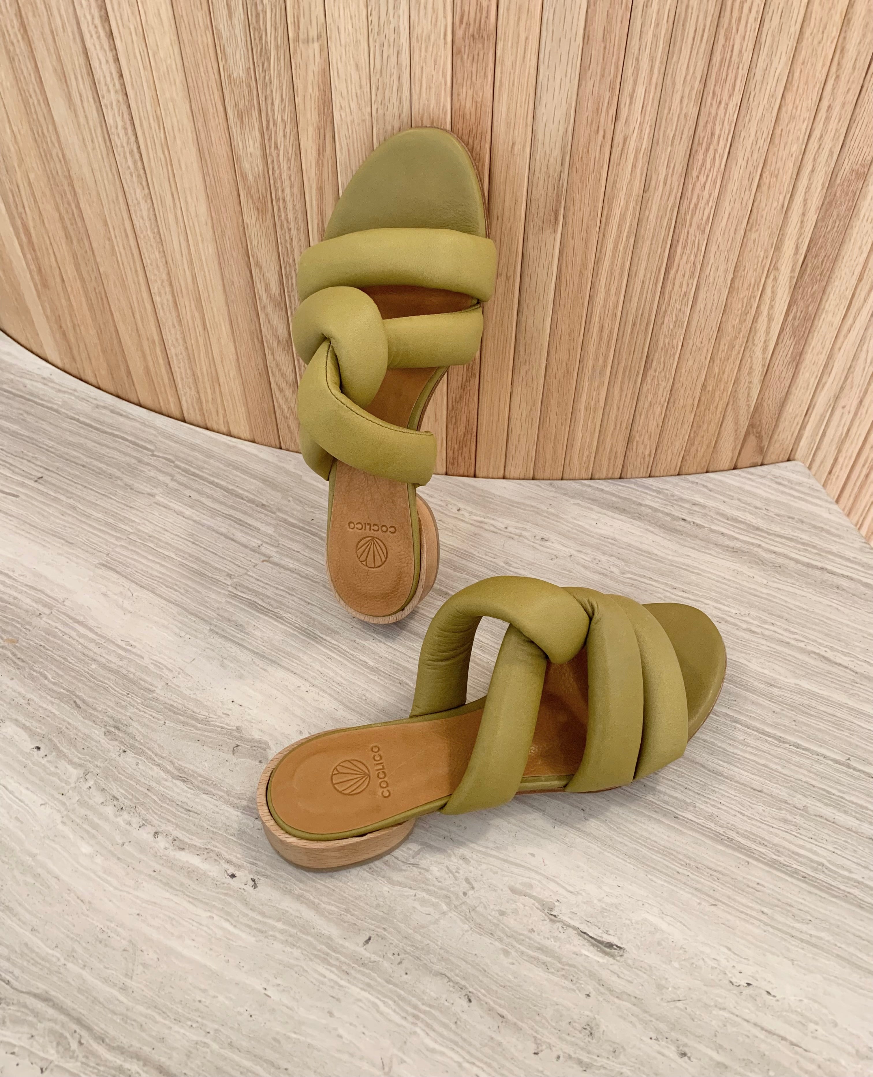 View of Coclico Everly Sandal in Torbollino Olive leather. A sandal with padded straps that twist over the arch, raised two-part leather sole.