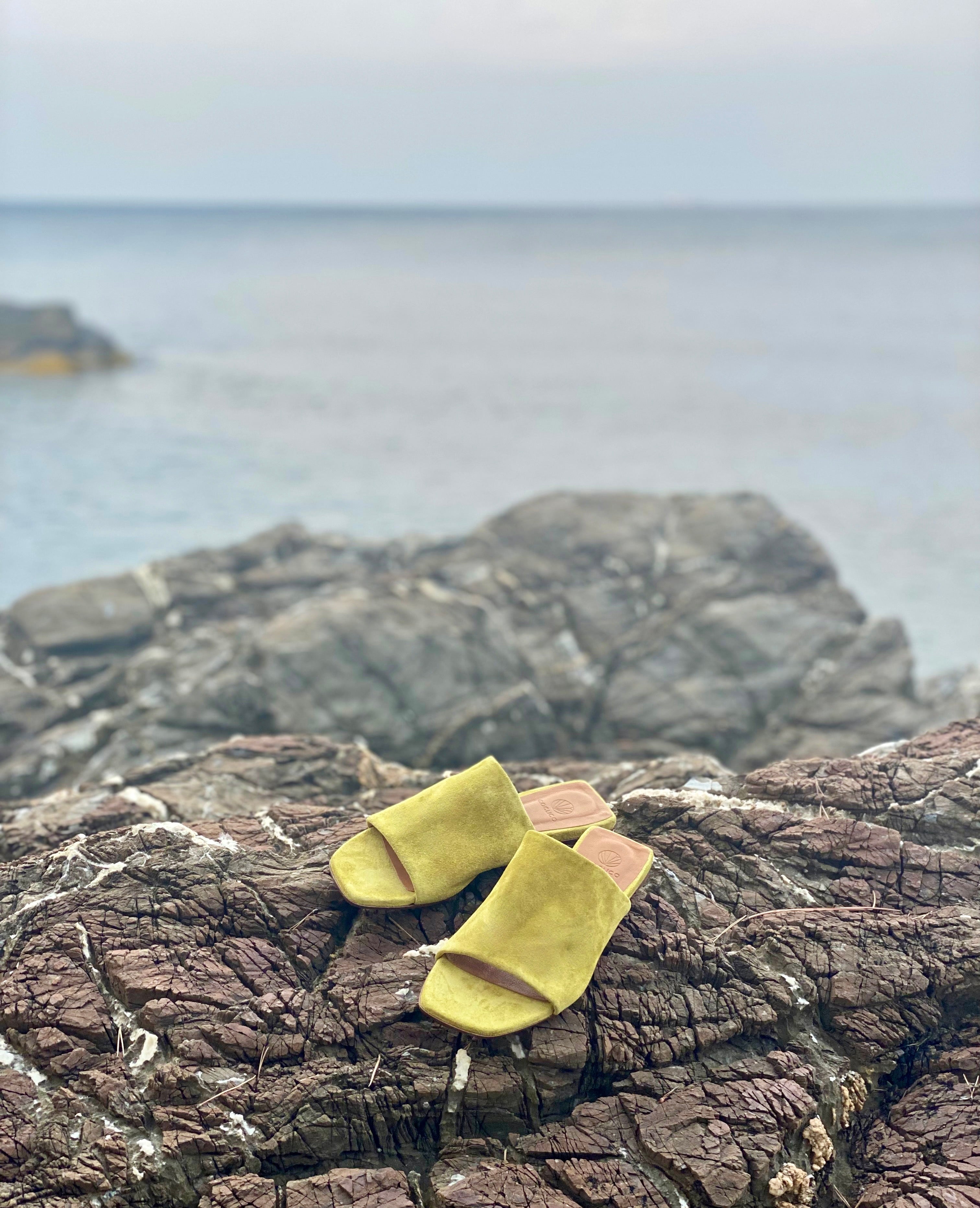 The Ferhana sandals on rocks at the sea.