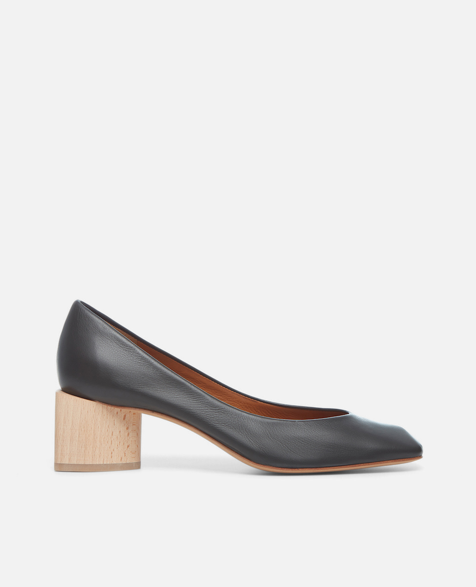 Side view of a black leather pump with a square toe and a solid architectural, natural wood block heel on a white background