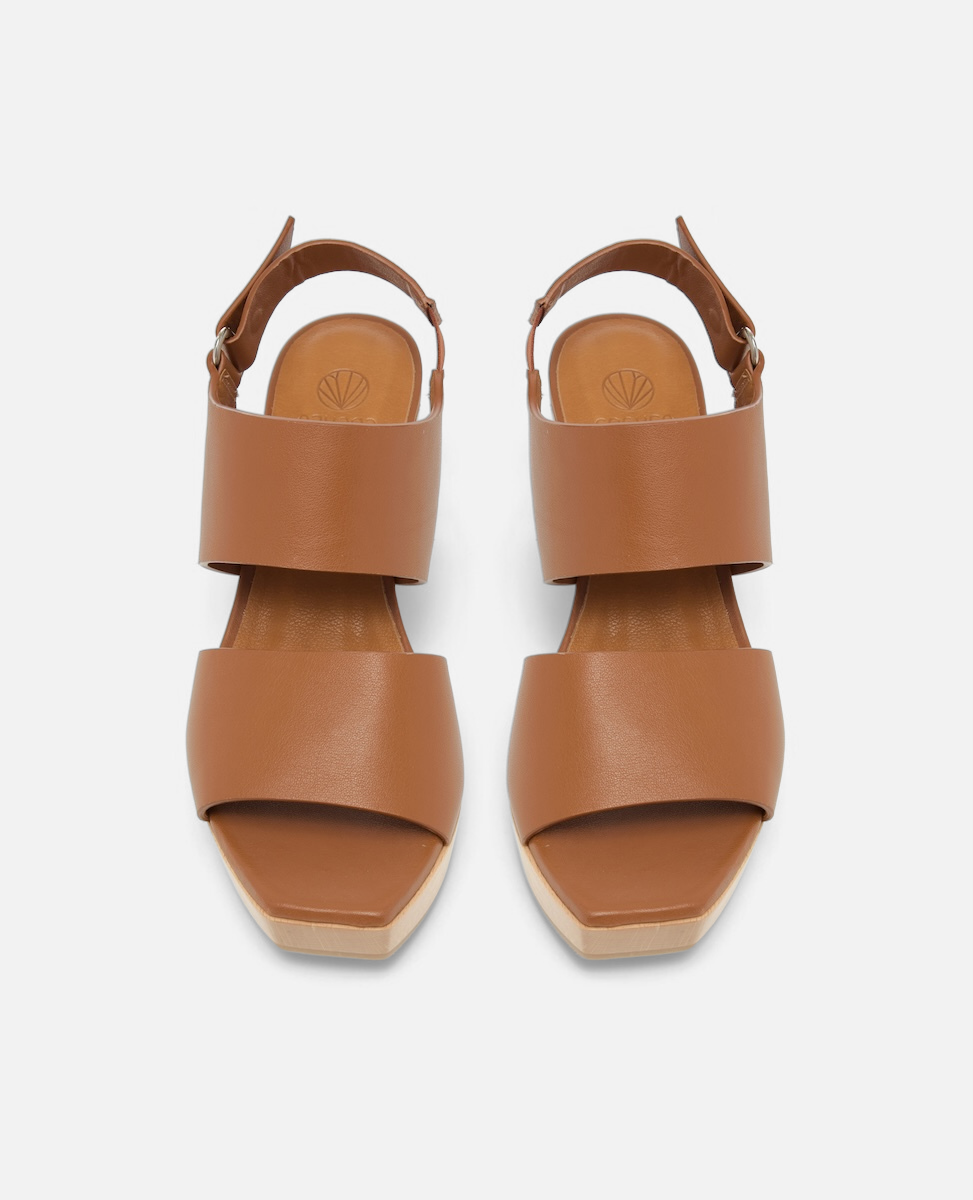 Brown leather clog sandals with wide straps, a closed back, and a flat, light-colored wood sole.