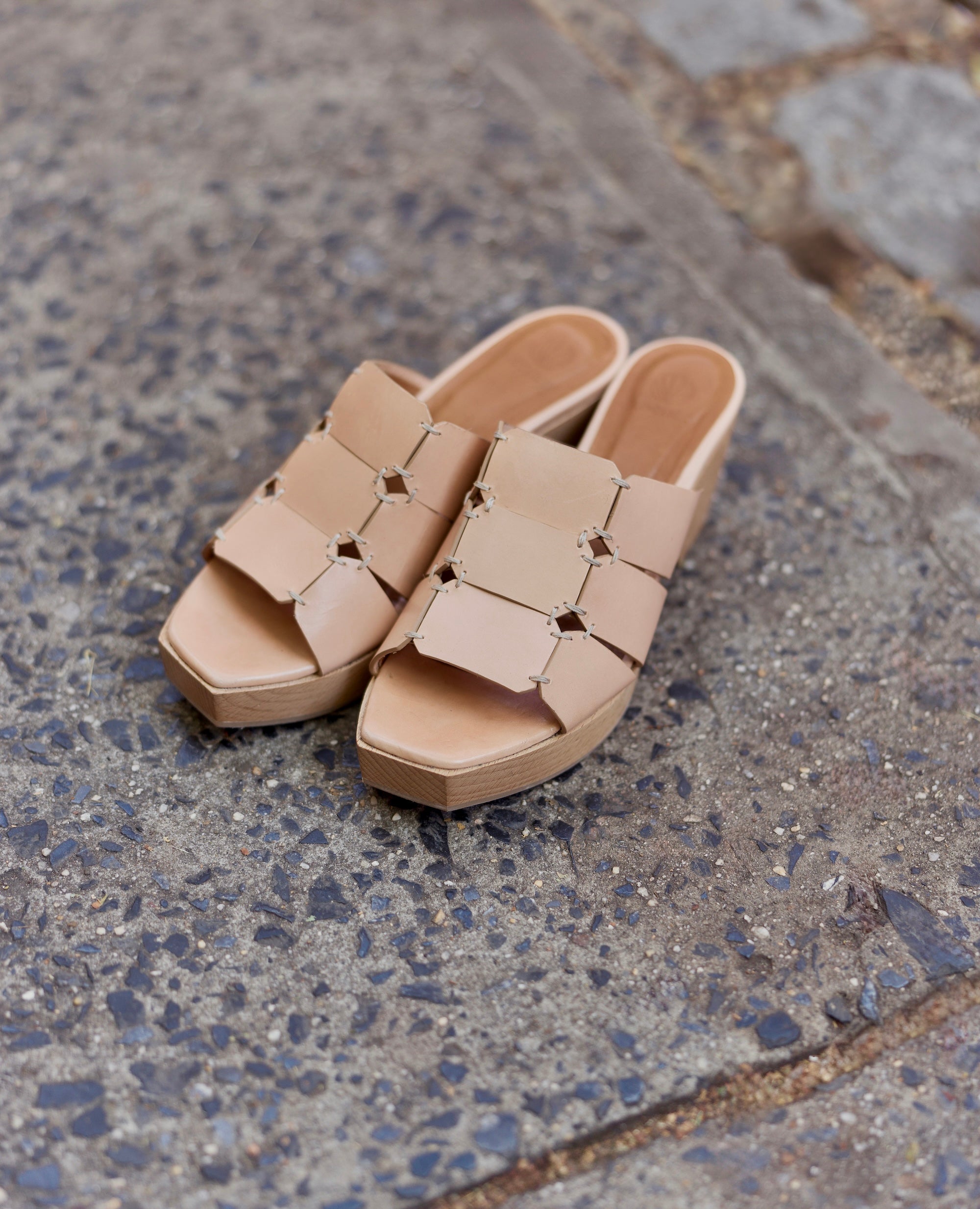 Beige sandals with a geometric design on pavement