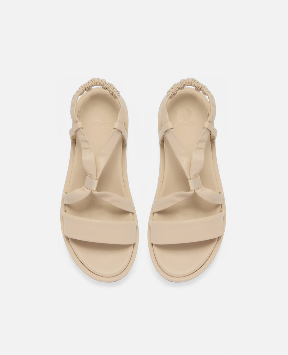 Top view of a milky white leather slingback footbed sandal with soft tubular straps, brushed-metal keeper detail, and a cushioned platform sole on a white background