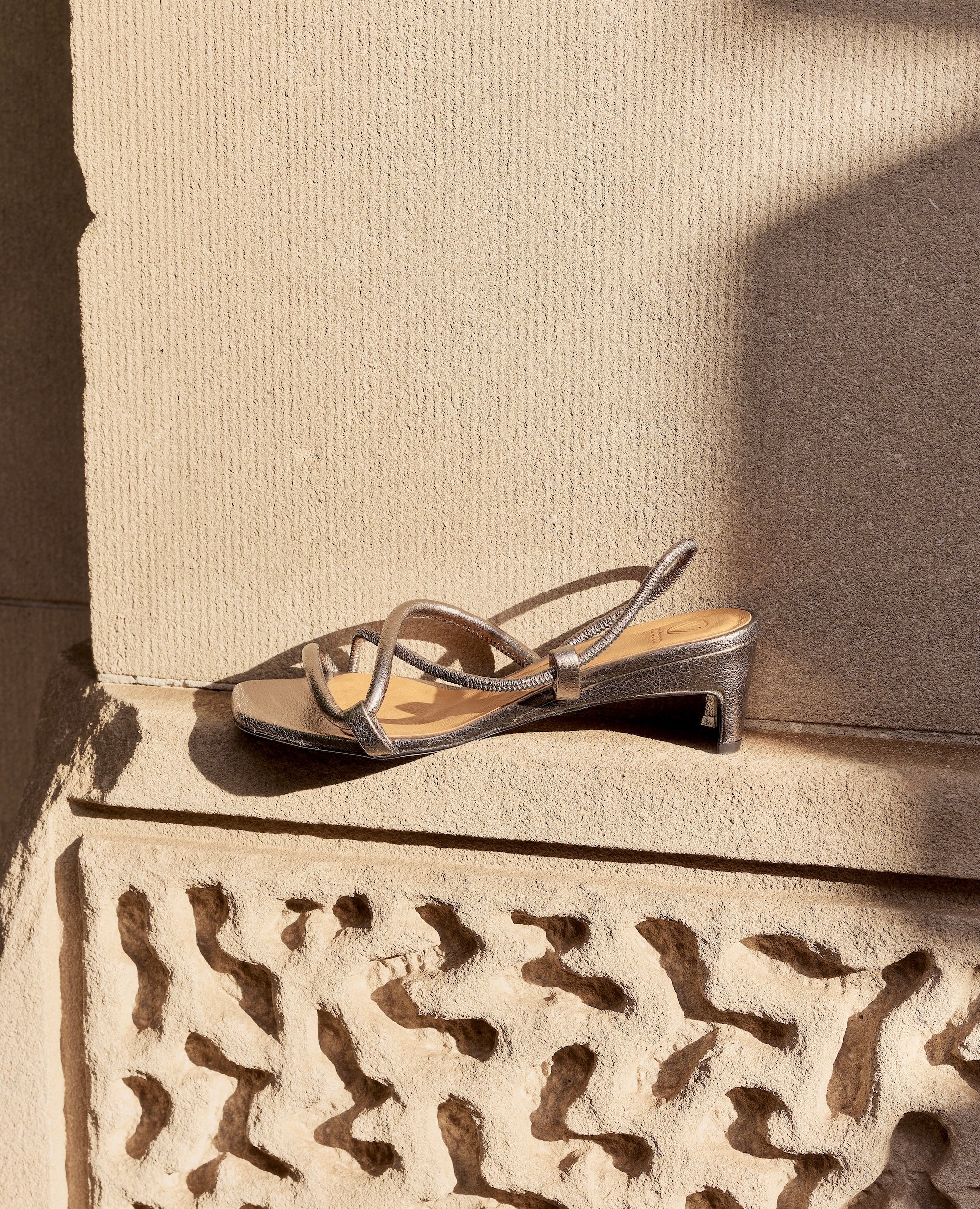 Dark Silver mid-heeled sandal on a textured stone surface
