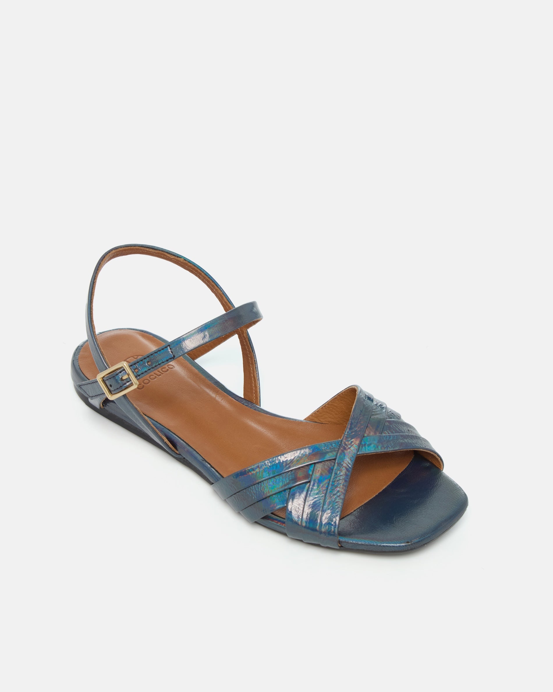 Angled view of a deep blue iridescent metallic leather sandal with slim crisscross straps, buckle quarter strap, and a square toe on a white background
