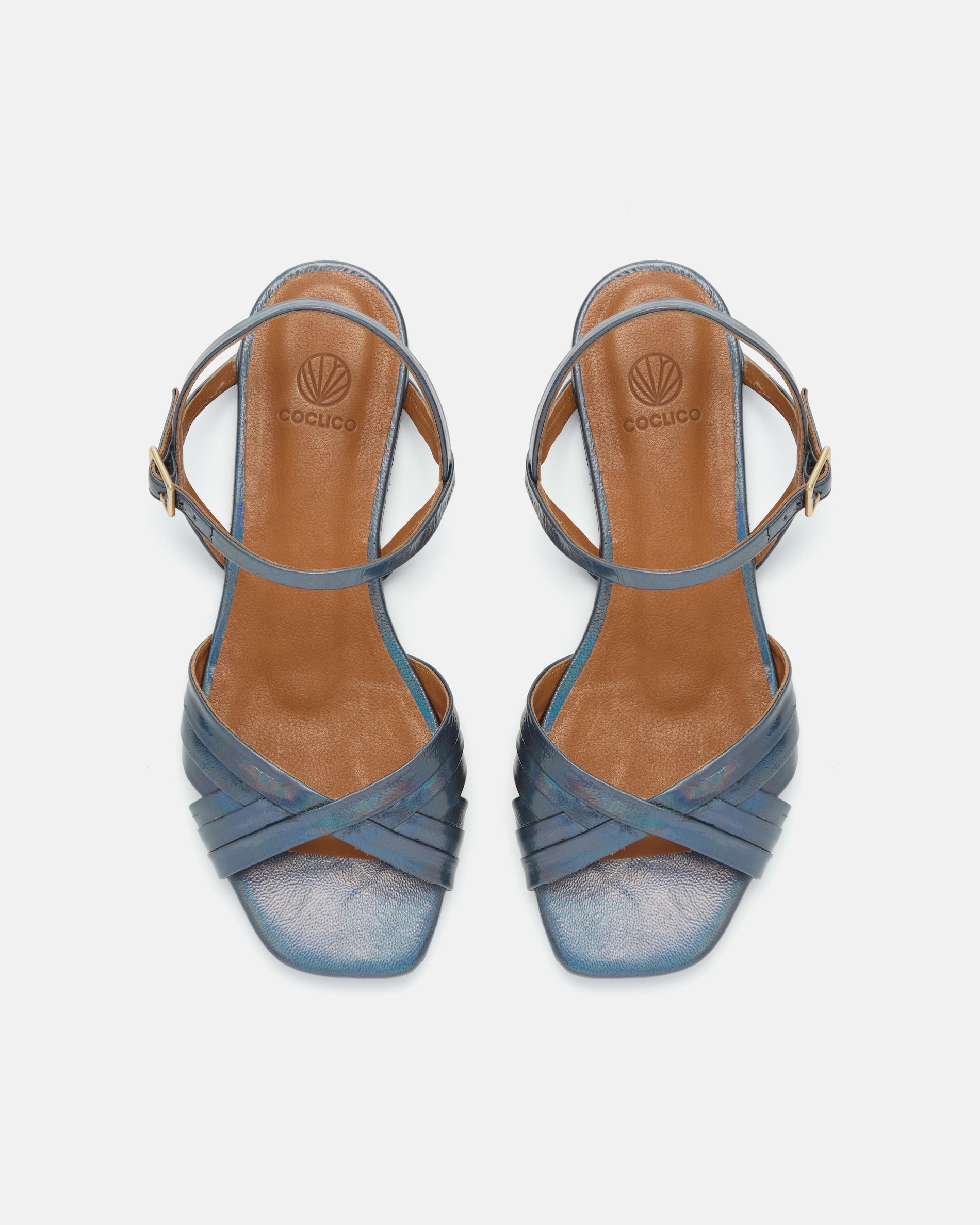 Top view of a deep blue iridescent metallic leather sandal with slim crisscross straps, buckle quarter strap, and a square toe on a white background