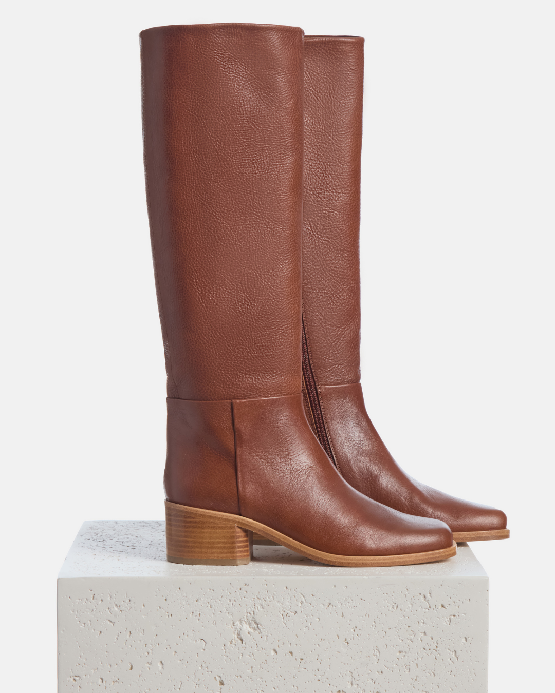 Coclico Alto Boot in Cuero, tan leather knee high boots styled on a stone plinth