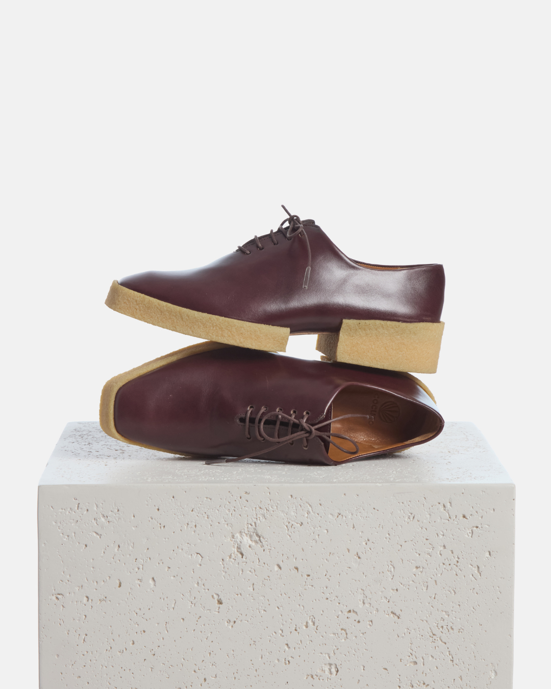 Coclico Beech Oxford in Oxblood leather, lace up oxfords with natural crepe soles styled on a stone plinth