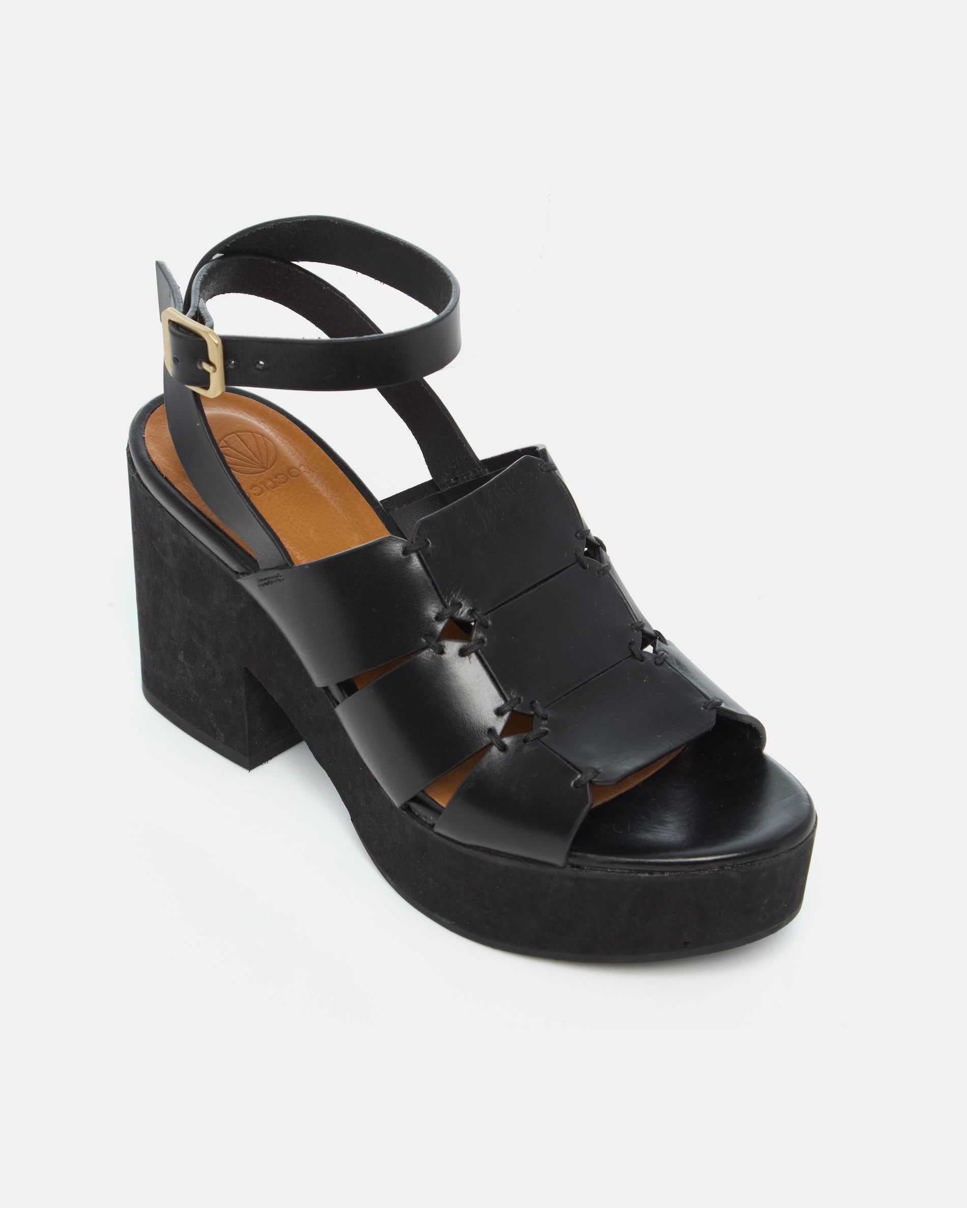 Angled view of a black vachetta leather platform sandal with octagonal cage straps, hand-stitched detailing, slim ankle strap with buckle, and a solid cork heel and platform, on a white background.