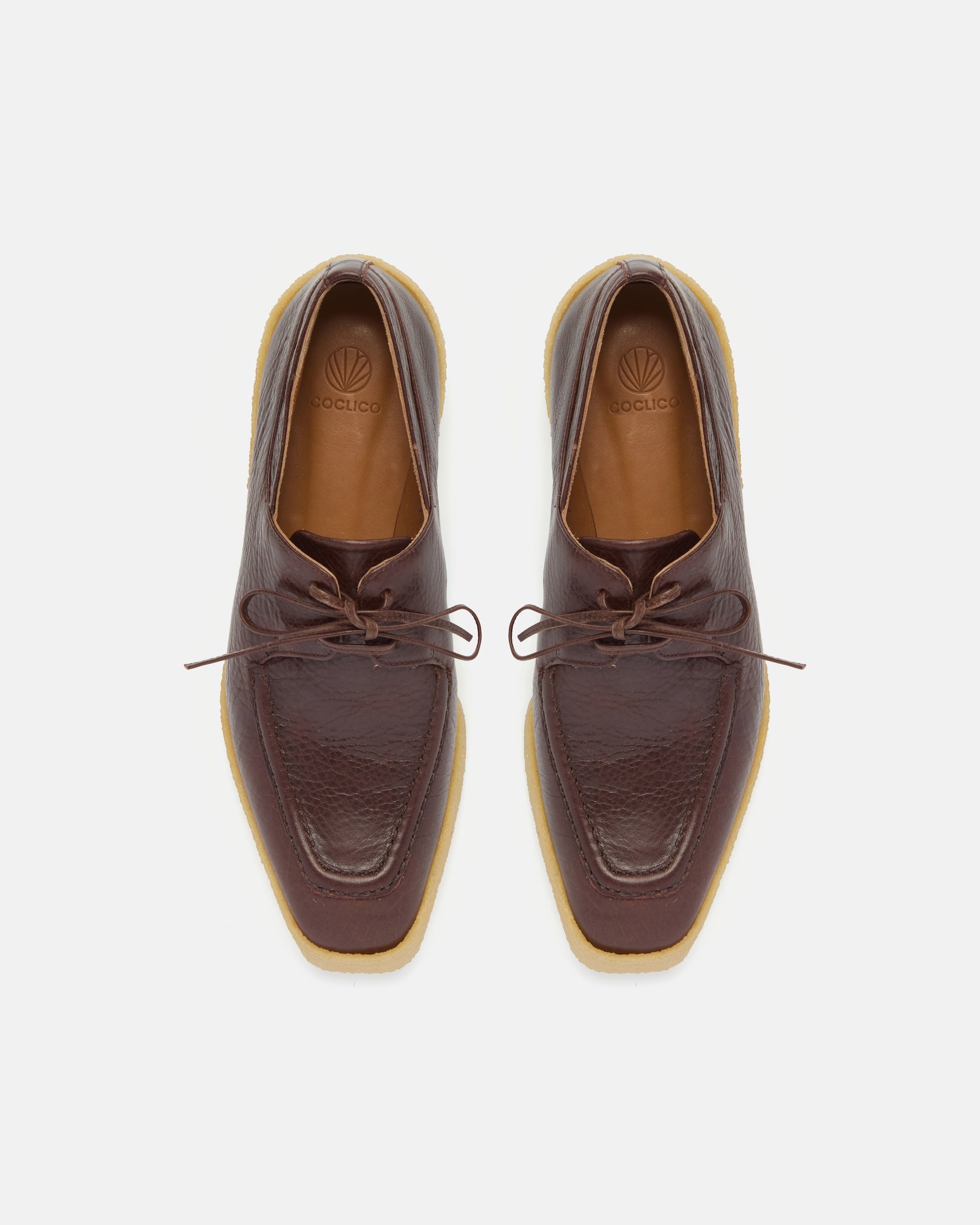 Pair of brown leather shoes with a crepe split sole on a white background