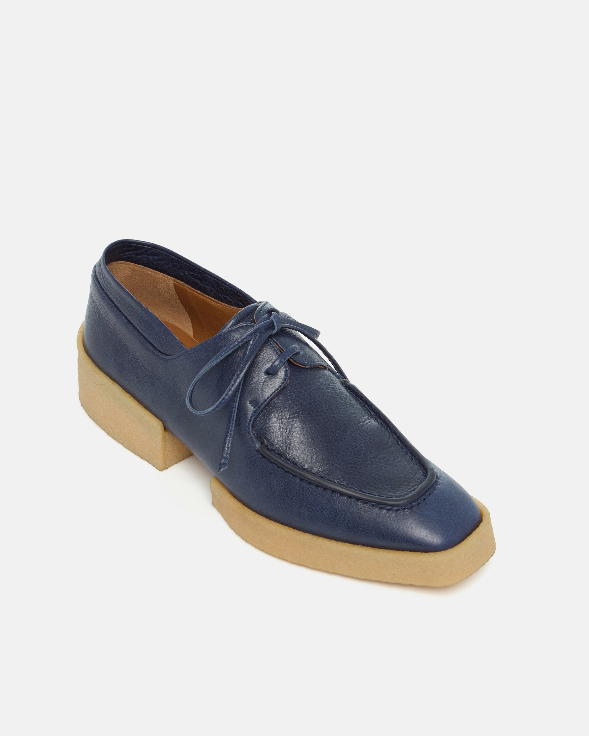 Navy blue loafers with a crepe split sole on a light gray background