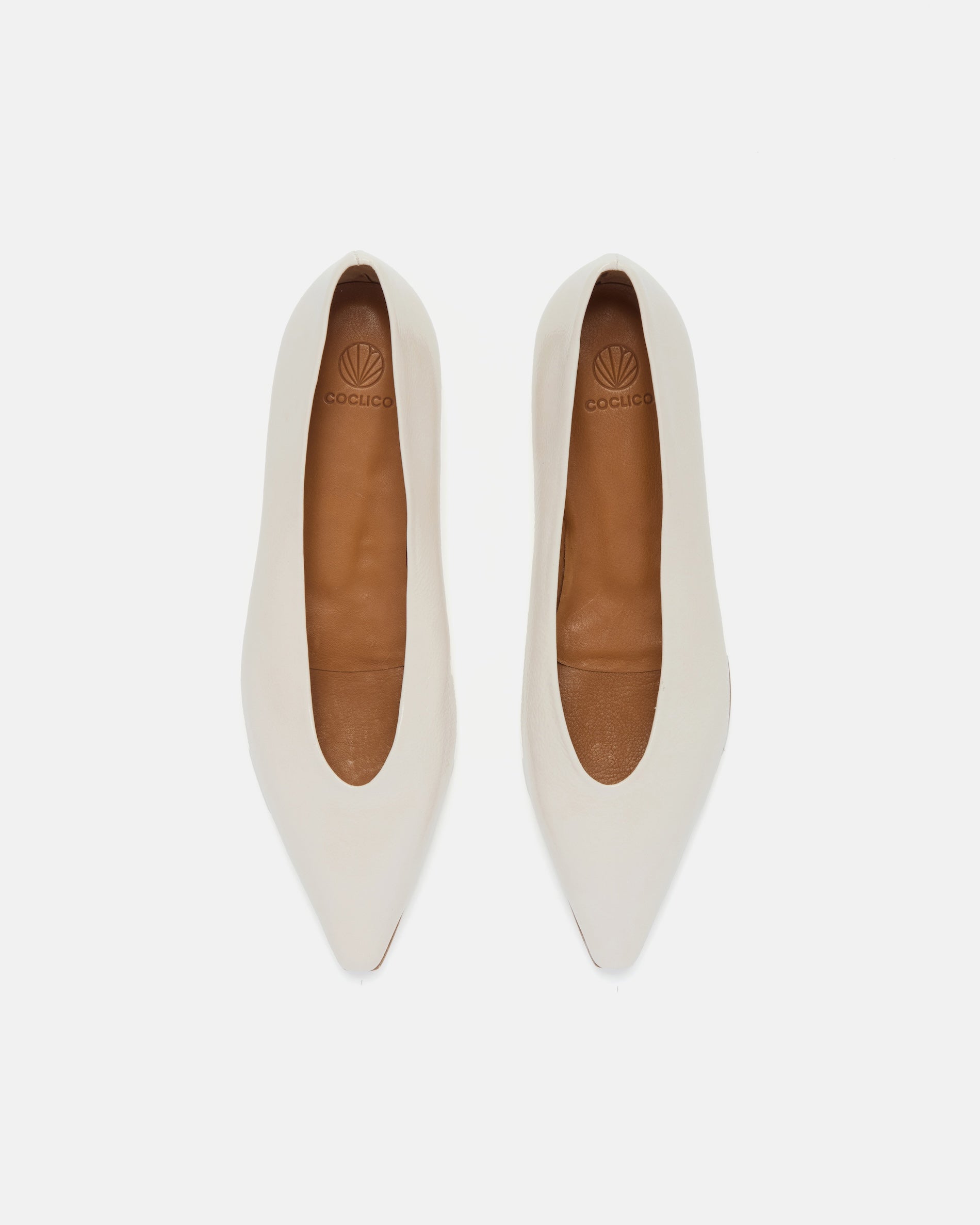 Top view of a off-white patent leather pointed-toe flat with clean lines and a flexible leather sole, on a white background.