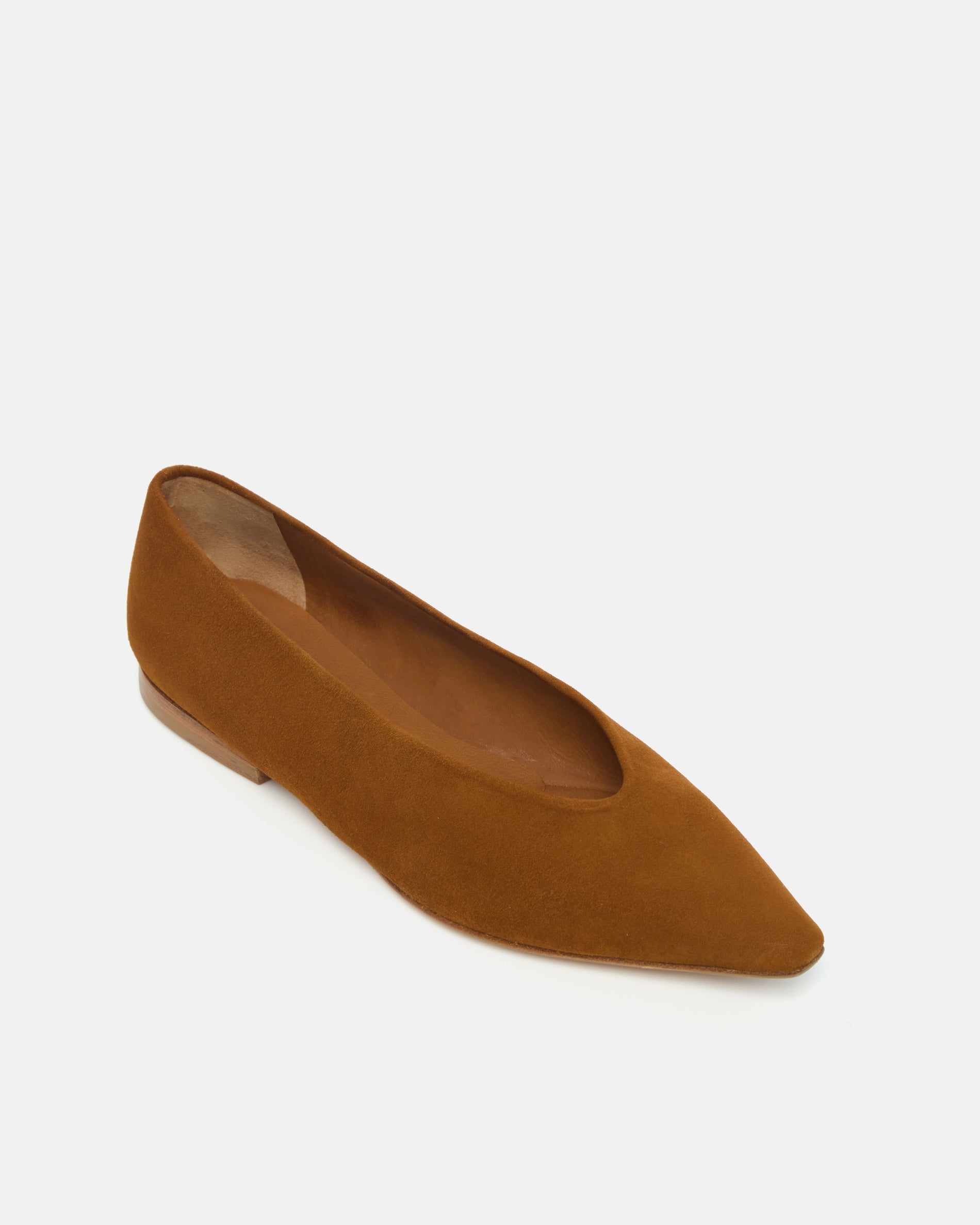 Angled view of a warm brown suede pointed-toe flat with clean lines and a flexible leather sole, on a white background.