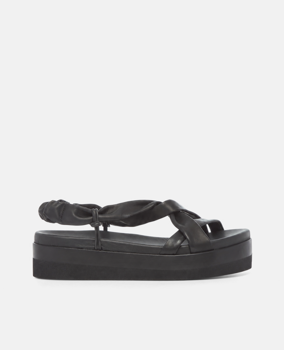 Side view of a black Coclico tubular leather sandal with a platform sole on a grey background