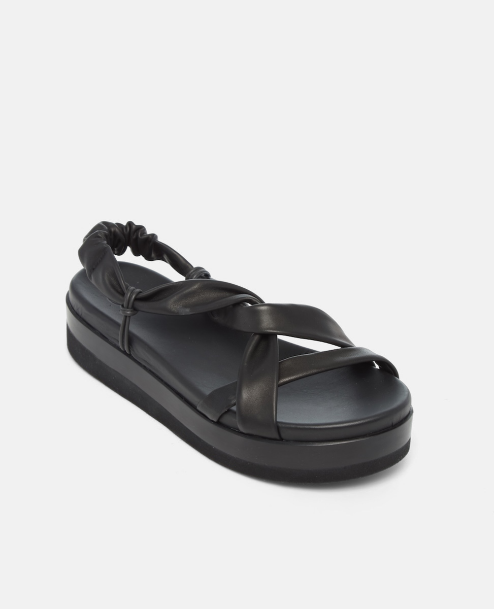 Angled view of a black Coclico tubular leather sandal with a platform sole on a grey background
