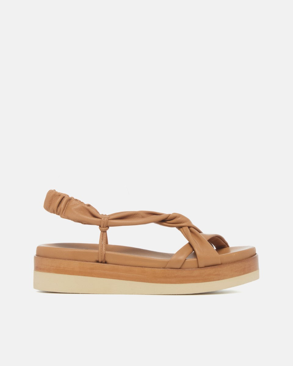 Side view of pale brown leather wedge sandal with softly twisted straps, elasticized back strap, and a lightweight EVA platform sole on a white background.