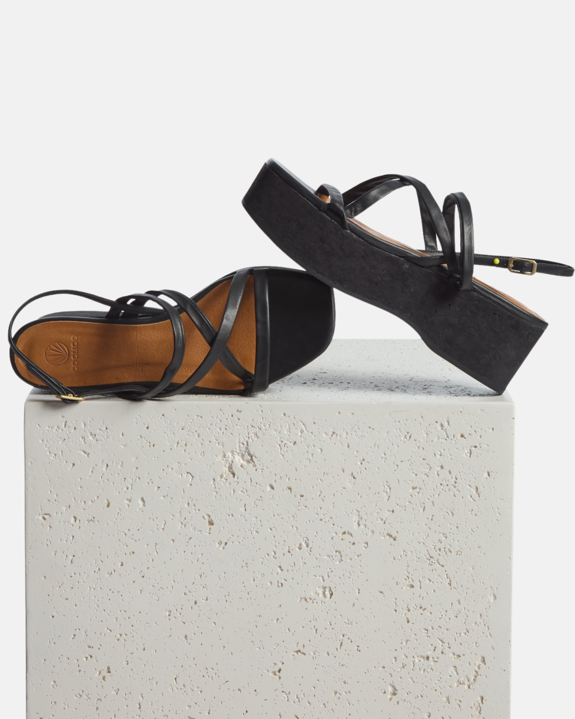 Wedge on a plinth: black leather cork wedge sandal with slim crisscross straps, adjustable slingback, and a sculptural cork platform sole