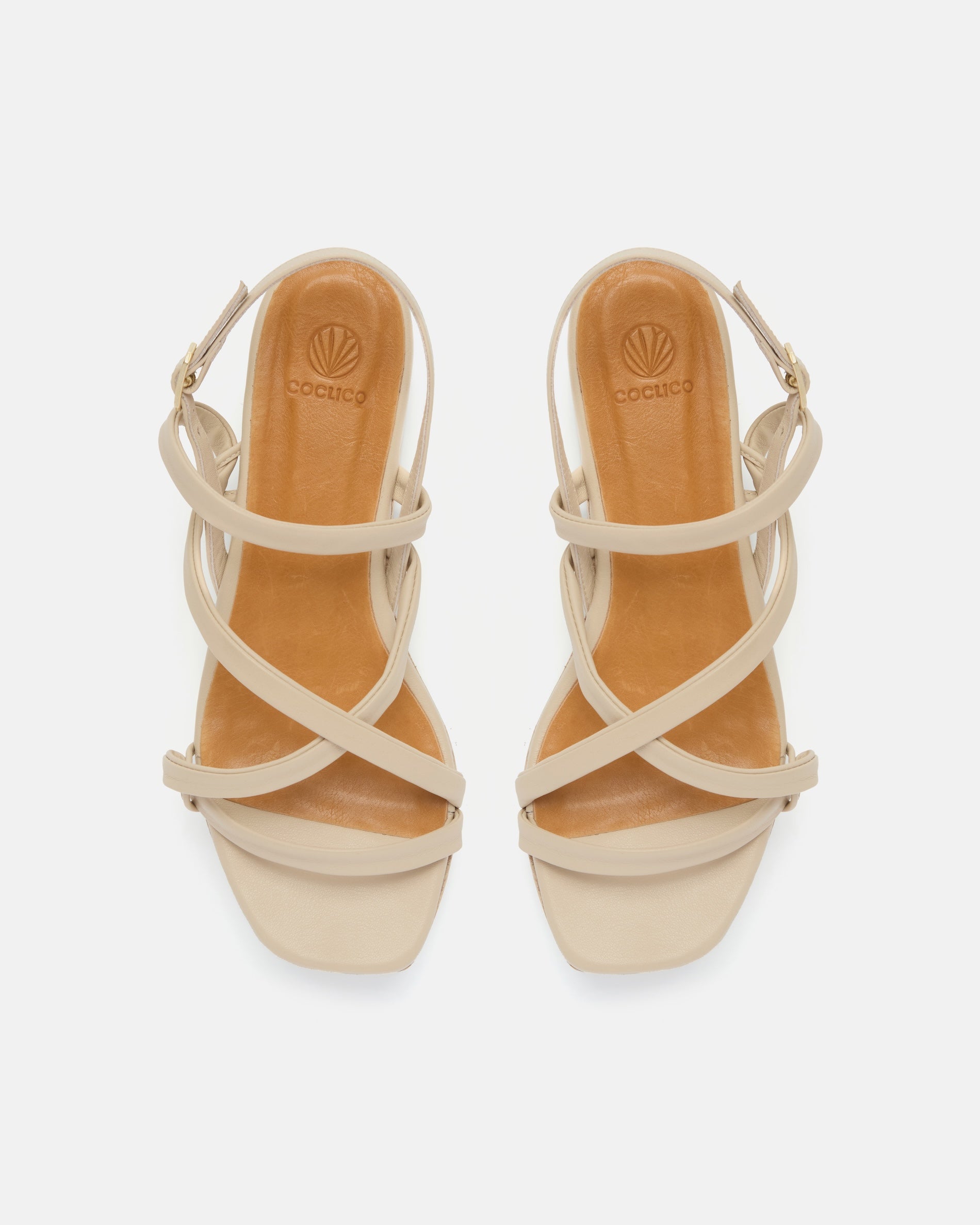 Top view of a off-white leather cork wedge sandal with slim crisscross straps, adjustable slingback, and a sculptural cork platform sole