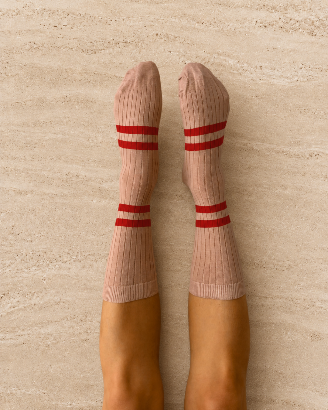 Escuyer Pink socks with red stripes worn by a person on a light gray background