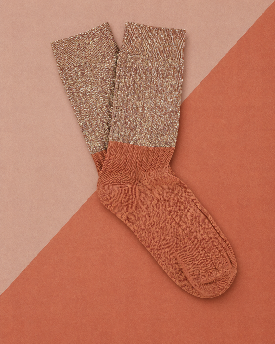 Escuyer Lurex Block socks with a sparkling Lurex top and Arabian Spice ribbed foot, laid flat on a two-tone terracotta background