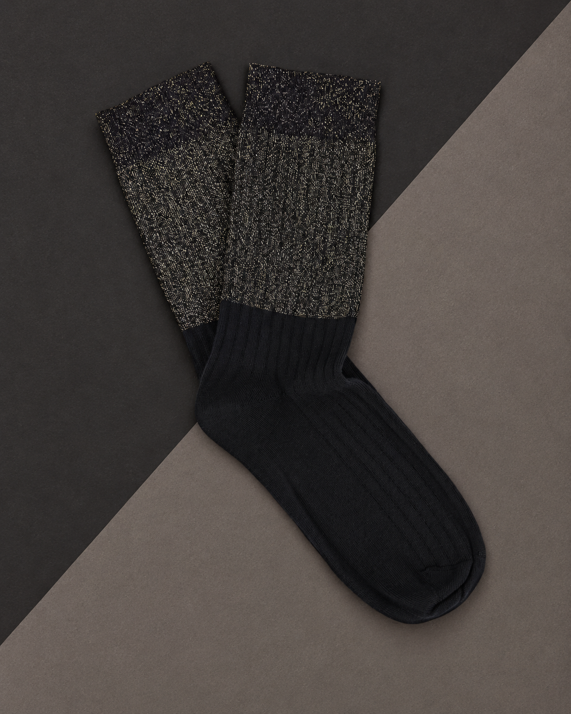 Escuyer Lurex Block socks with a sparkling gold Lurex top and black ribbed foot, laid flat on a two-tone grey background