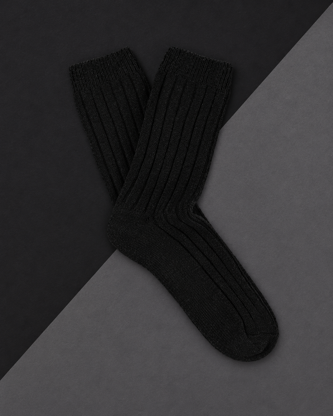 Escuyer cashmere crew socks in Black laid flat on a two-tone grey background
